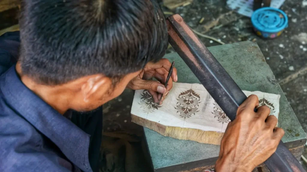 An Indian artisan hand-carving intricate floral patterns on a wooden block, showcasing traditional craftsmanship and India's rich handicraft heritage.